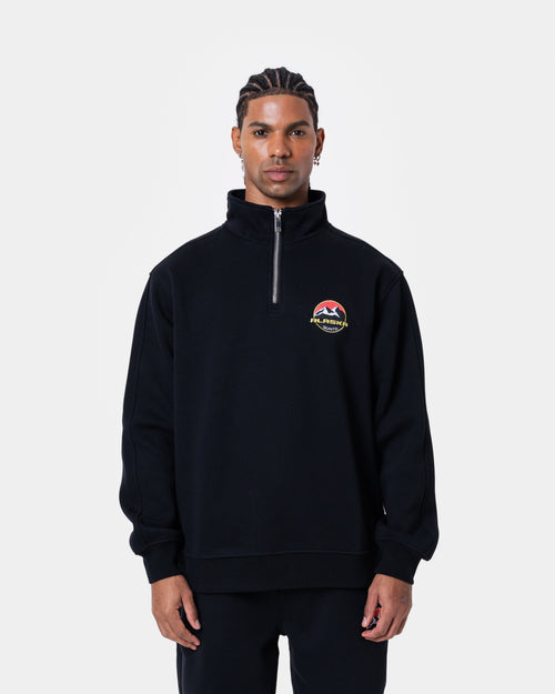 ALASKA BADGE BLACK HALFZIP worn by model in black, showcasing short zipper and loose fit design.