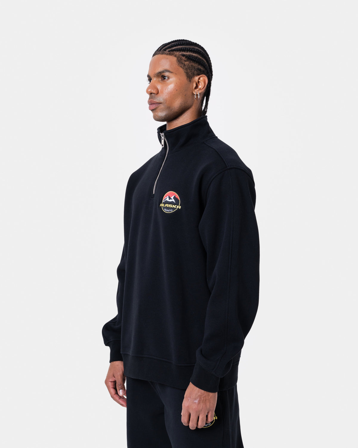ALASKA BADGE BLACK HALFZIP worn by model, featuring a short zipper and soft black fabric.