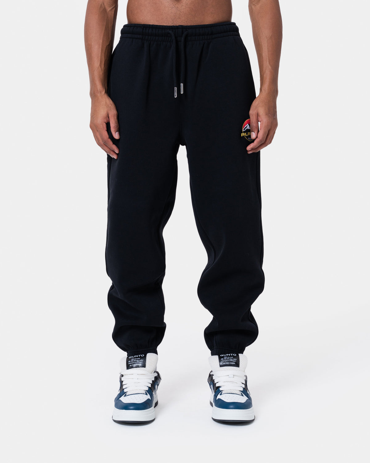 ALASKA BADGE BLACK JOGGER displayed on model, featuring loose fit, side and back pockets, elastic waistband.