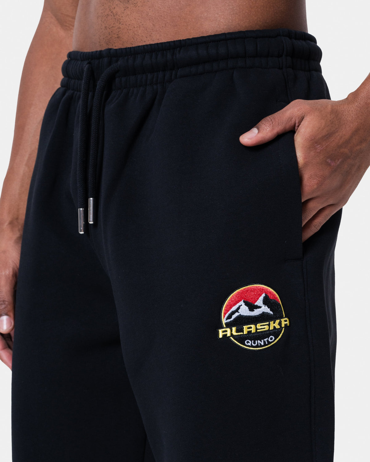Close-up of ALASKA BADGE BLACK JOGGER showcasing the embroidered logo and side pocket.